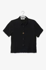 Camisa negra de manga corta con cuello clásico y cierre frontal con botones.