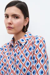 Camisa de manga larga con cuello clásico y estampa geométrica retro en tonos azul, rojo y blanco.