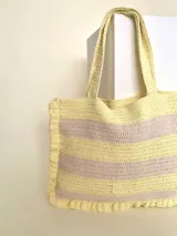 Bolso tipo tote tejido a crochet, con hilo 100% algodón, a rayas horizontales color crema y lila, con volados en los bordes y manijas reforzadas.