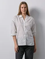 Camisa texturada blanca con líneas verticales negras, marca Hester & Orchard. Cuello a la base, escote en V y abertura central con botones. Manga ¾ con terminación fruncida.