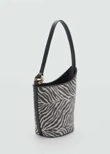 Bolso tipo bucket con estampado de cebra, asa corta y cierre de botón magnético.