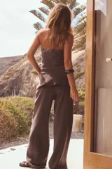 Pantalón marrón de tela fluida, corte recto, tiro medio y cintura elástica ajustable con cordones. Incluye bolsillos laterales ocultos en la costura.