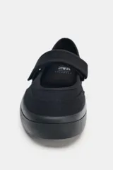 Bailarinas negras de tela con puntera redondeada, suela de goma y tira con cierre adhesivo.