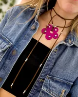 Gargantilla tipo choker con dije de flor fucsia de acrílico con strass y tiras de gamuza marrón con cuentas plateadas.