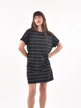 Vestido corto negro de manga corta y cuello redondo, con estampado de rayas horizontales blancas. Presenta un bolsillo de parche en el pecho.