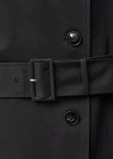 Abrigo largo negro de algodón con cinturón, cuello con solapa y doble botonadura.