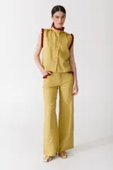 Pantalón de jean azul oscuro, de corte acampanado, con bolsillos delanteros con detalle de volados.