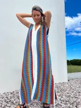 Vestido largo de tejido con diseño geométrico en tonos celeste, marrón, rojo y blanco. Tiene escote en V y aberturas laterales.