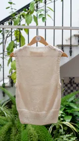 Chaleco tejido color crema, con cuello alto y sin mangas.