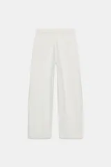 Pantalón de jean blanco de tiro bajo con cinco bolsillos y corte amplio. Detalle de cintura doblada. Cierre frontal con cremallera y botón metálico.