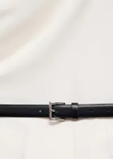 Mono largo color blanco, con cuello drapeado, tirantes anchos y cinturón negro desmontable con hebilla.