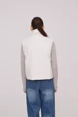 Chaleco blanco con cuello alto y cierre frontal con cremallera.