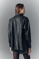 Camisa de cuero ovino negro con efecto arrugado, de moldería amplia, con cuello camisero y botones a presión con logo.