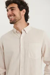 Camisa azul marino de lino y algodón, con cuello abotonado, manga larga con puños enrollados, bolsillo de parche en el pecho y cierre frontal con botones.