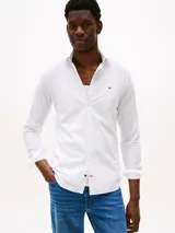 Camisa blanca de popelina con tecnología flex, corte slim, cuello con botones, cierre con botones, manga larga y logo de Tommy Hilfiger bordado en el pecho.