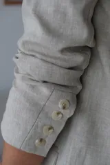 Blazer beige de lino, con solapas de muesca, cierre frontal con dos botones y bolsillos laterales con solapa.