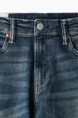 Jean de corte slim, color azul con efecto gastado, de cinco bolsillos, tiro medio y pierna recta.