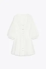 Vestido corto blanco con bordados perforados, escote en pico, manga tres cuartos abullonada, cintura entallada con nido de abeja elástico en la espalda, forro interior y cierre frontal con botones.