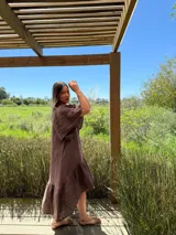 Vestido largo color beige, de corte amplio, con mangas cortas abullonadas y volado en el ruedo.