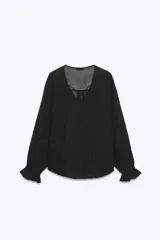 Blusa negra semitransparente con escote en pico, cordón ajustable y mangas largas con elástico en los puños.