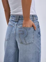 Pantalón de jean color beige, de corte wide leg, con bolsillos delanteros y traseros, y ruedo desflecado.