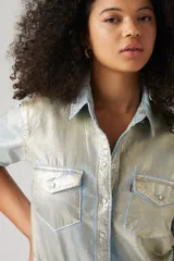 Camisa de manga larga con botones, confeccionada en tela brillante color celeste con efecto óptico. Tiene cuello clásico, dos bolsillos con solapa abotonada en el pecho y corte recto.