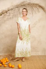 Vestido largo color blanco con estampado floral en tonos verdes y amarillos, con escote en V y mangas cortas.
