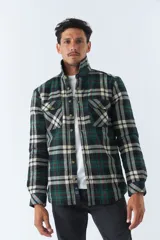 Sobrecamisa de algodón para hombre con interior de corderito, estampado a cuadros en tonos negro, blanco y azul. Tiene cierre de botones, bolsillos tipo cartera y logo en goma. El modelo usa talle M.