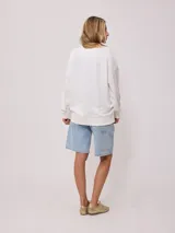 Sweater color crema con estampado frontal de motivos playeros y bordado. Confeccionado en 60% algodón y 40% poliéster.
