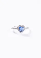 Anillo plateado con dije de corazón azul rodeado de pequeñas circonitas blancas.