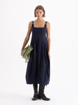 Vestido midi azul marino con escote cuadrado, breteles ajustables con hebillas metálicas y falda tipo balloon. Cuenta con cierre lateral invisible y bolsillos ocultos.