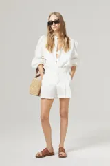 Camisa blanca de lino con cuello mao, mangas largas abullonadas con puño elástico y corte holgado.