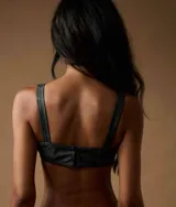 Top corto tipo corset negro con tirantes ajustables y cordones frontales.