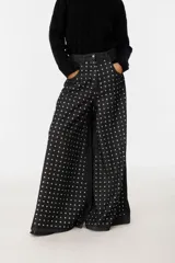 Pantalón wide leg gris con tachas plateadas en el frente.