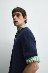 Cárdigan azul marino de manga corta tejido en hilatura con lana y alpaca, de textura suave. Tiene cuello redondo, rib en los bordes y cierre frontal con botones. Edición especial Harry Lambert for Zara x Disney.