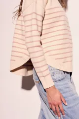 Sweater color crema con rayas horizontales finas color marrón claro, de corte holgado y mangas largas.