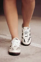 Zapatillas Adidas Samba con estampado animal print en blanco y negro, detalles en cuero beige y suela de goma color caramelo.