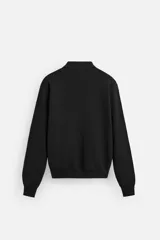 Polo de manga larga color negro, de punto tejido en hilatura de algodón, corte relaxed fit, con cuello solapa y cierre frontal de botonadura.