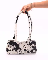 Cartera baguette de cuero con estampado animal print blanco y negro. Tiene forro interior, un bolsillo amplio y broches laterales para ajustar el tamaño.