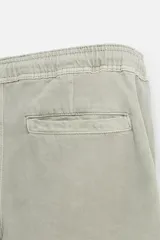 Bermuda color beige de denim de algodón, corte relaxed fit, con cintura elástica ajustable con cordón, bolsillos frontales y traseros.