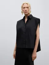 Camisa negra sin mangas con cuello camisero y cierre frontal con botones, diseño con capas en la espalda.