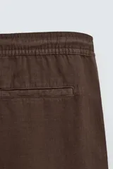 Bermuda de algodón color marrón oscuro, de corte regular fit, con cintura elástica ajustable mediante cordón. Presenta bolsillos laterales y un bolsillo trasero de vivo.