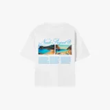 Camiseta blanca de corte holgado con estampado de fotos de playas y texto de la marca Nude Project en color celeste.