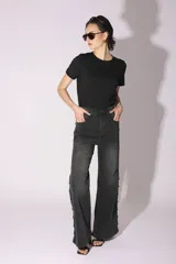 Pantalón de jean gris oscuro con lavado gastado, corte acampanado y tachas plateadas en los laterales.
