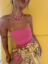 Falda corta tipo pareo de color amarillo con estampado de palmeras y motivos gráficos en contraste. Presenta un diseño ajustable mediante un lazo lateral y está confeccionada en una mezcla de viscosa y lino.