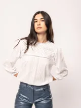 Blusa oversized de algodón blanca, con escote redondo y mangas tres cuartos, que presenta una mezcla de bordados y texturas.