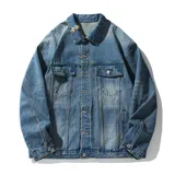 Campera de jean de color azul claro con efecto gastado y roturas. Presenta cuello, cierre frontal de botones, dos bolsillos con solapa en el pecho y bolsillos laterales a la altura de la cintura.