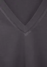 Camiseta gris con cuello en V, manga corta y detalle de tachuelas en los hombros.