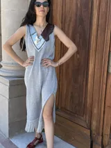 Vestido tejido plateado con lurex, escote en V profundo con apliques de cuero bordados a mano, tajos laterales y flecos en el ruedo.