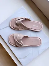 Sandalias bajas color rosa nude, sin talón, confeccionadas en cuero, con tira ancha sobre el empeine con detalle de nudo.